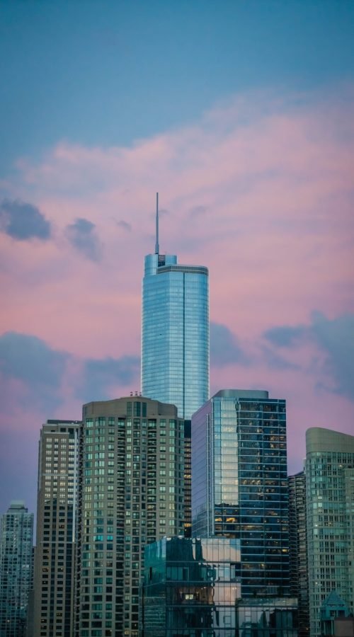 A tall business building skyscraper in Chicago, US, with beautiful pink clouds in the blue sky